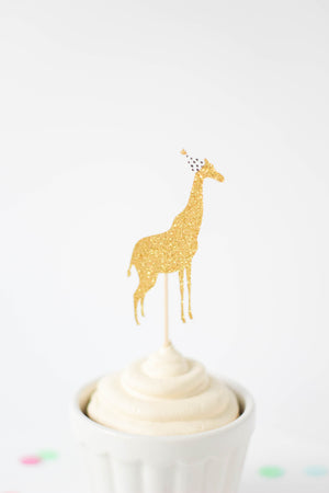 Gold zoo giraffe cupcake topper with mini party hat on top of a white cupcake.