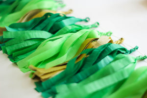 Close up up a hand made and hand rolled tissue garland in the colors emerald, green, lime, and gold perfect for any occasion or St. Patricks Day!