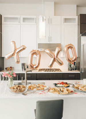 Giant rose gold balloons spell out XOXO.